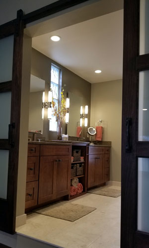 photo looking into bathroom with warm wood double vanity, tile floor