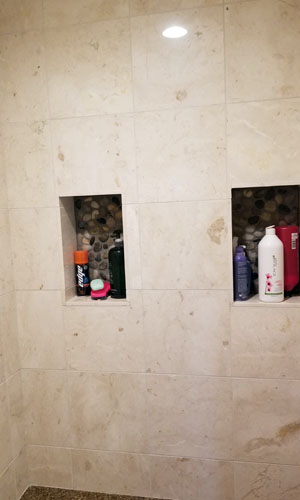 photo of stone tile shower with soap recesses backed with pebbles
