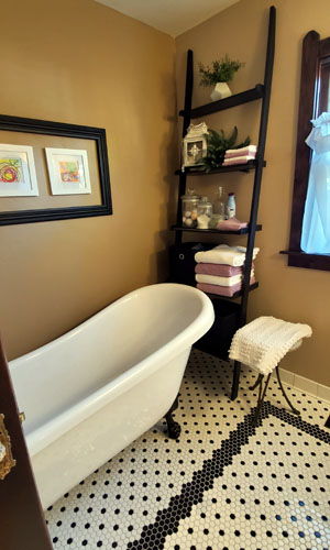 photo of clawfoot tub with mustard colored walls and black and white penny tile floors
