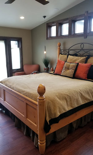 photo of bedroom with vaulted ceilings with high square windows above bed and warm wood floors