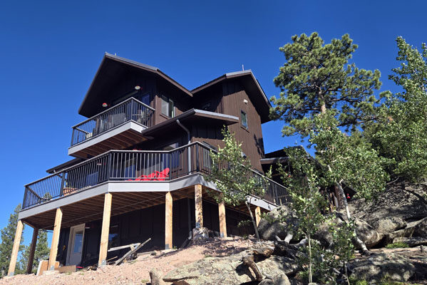 photo of exterior of tall brown house with lots of decks and railings on a slope