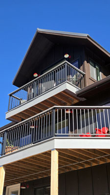 photo looking up at exterior of house with two levels of balconies with metal and wood railings