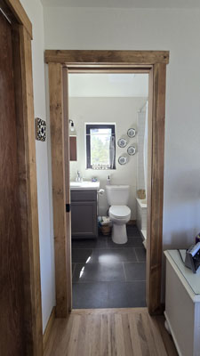 photo of interior of bedroom looking into bathroom with fir trim and wood and stone floors