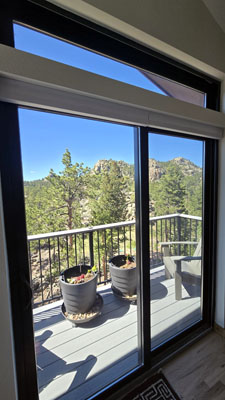 photo of large sliding glass doors with transom looking out to large balcony with railing and mountain views