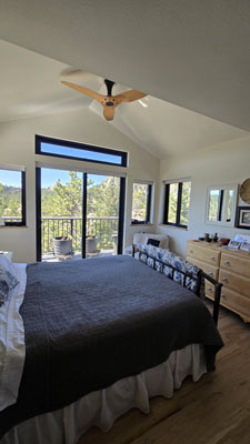 photo of bedroom with vaulted ceilings, wood ceiling fan, expansive windows