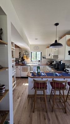 photo of kitchen with peninsula seating, white cabinets and wood floors