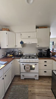 photo of white kitchen with white stove and warm wood floors