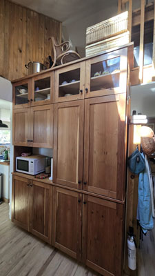 photo of built-in custom wood storage cabinets with some glass cabinet doors and an opening for a microwave