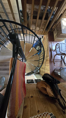 photo looking down at a small interior spiral staircase with wood treads and metal railing