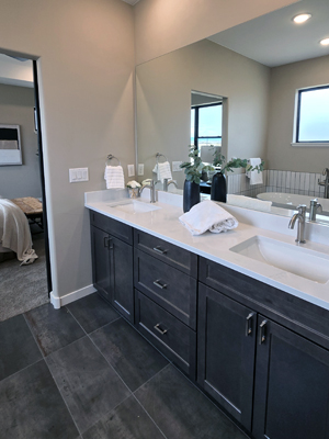 photo of bathroom vanity with dark wood cabinets, white countertop and dark wood tile floors