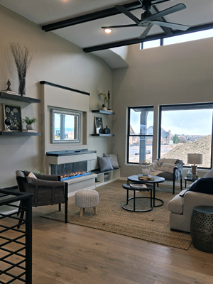 photo of large living room with high ceilings, dark beams, wood floors, and a wide fireplace