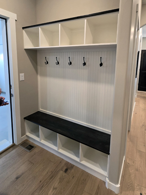 photo of empty mudroom with bench cubbies, hooks and wood floors