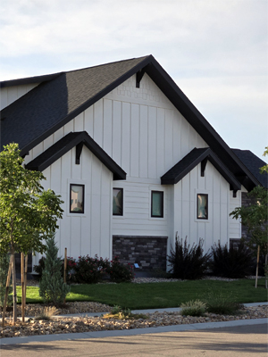 photo of house with gable roof bumpouts with wood brackets, white board and batten siding