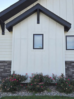 photo of gable roof bumpout with wood bracket, white board and batten siding with black trim