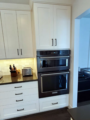 photo of kitchen with white cabinets, black stainless built-in microwave and wall oven